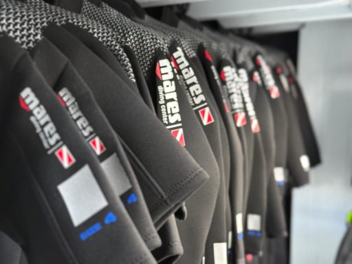 A row of neatly hanging Mares wetsuits prepared for divers before departure.